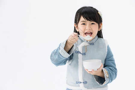 夹棉马甲穿着淡蓝色古装的可爱小女孩吃汤圆背景