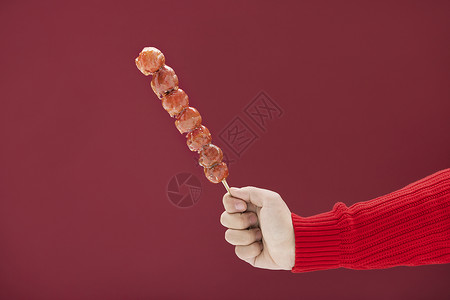 穿着红色毛衣的一只手拿着冰糖葫芦背景图片