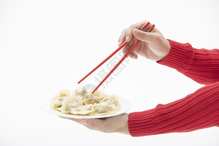 红色毛衣的手使用筷子夹饺子背景图片