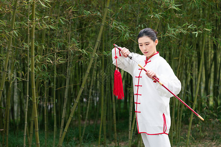 穿着练功服的女性在竹林拔剑背景