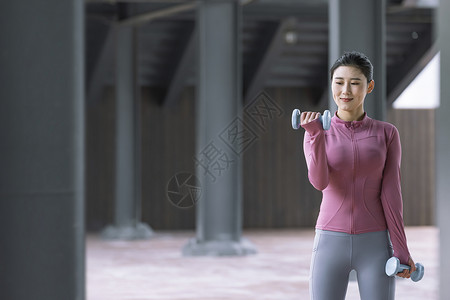 女性在户外用哑铃健身高清图片