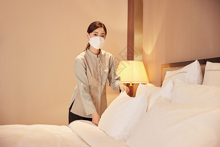 佩戴口罩酒店服务保洁员整理床铺背景