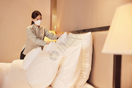佩戴口罩酒店服务保洁员整理床铺高清图片