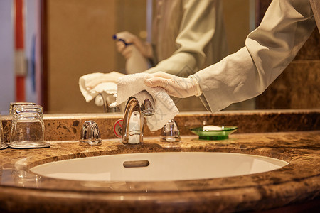 酒店保洁员整理清洁客房洗漱区域特写高清图片