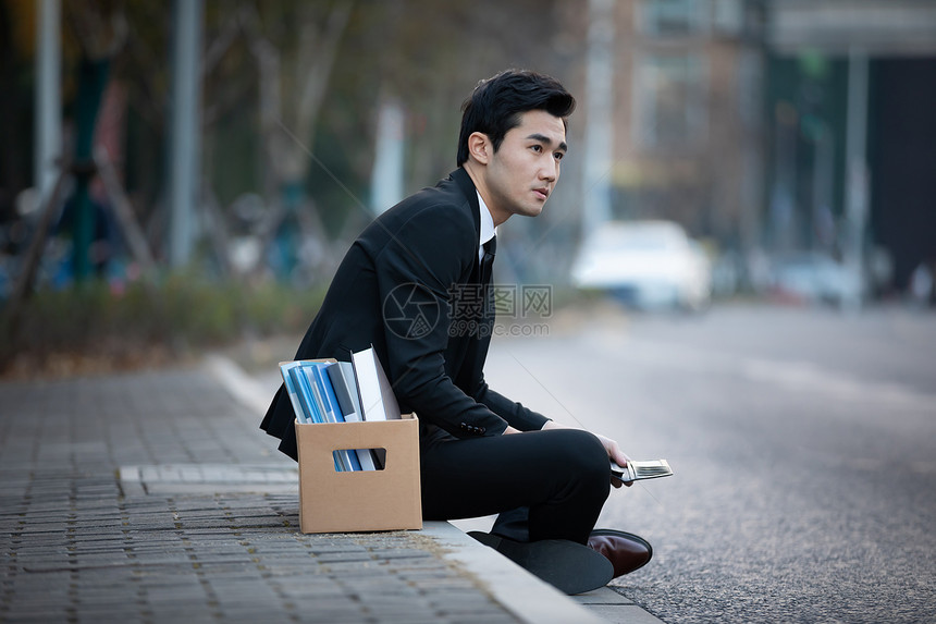 被炒鱿鱼的男性坐在街头图片