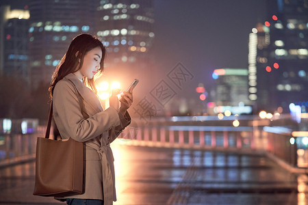 深夜加班的都市女性使用手机打车背景图片