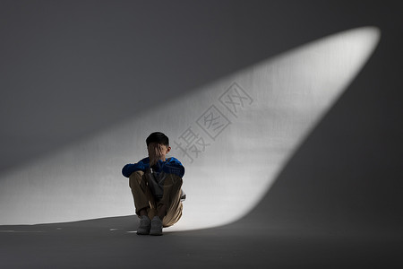 青少年自杀孤独的小男孩遭受欺凌坐在墙角背景