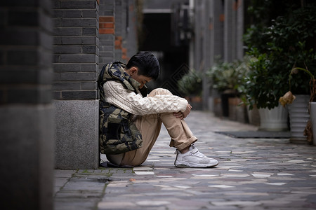 迷彩鞋孤独自闭的青少年遭受校园欺凌蜷缩在墙角背景