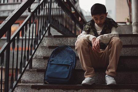反对霸凌孤独的青少年坐在楼梯背景