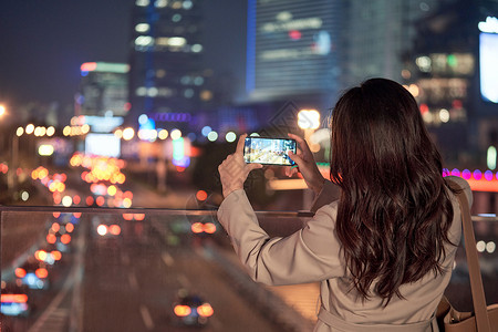 人物外拍素材使用手机拍夜景的都市女性背景