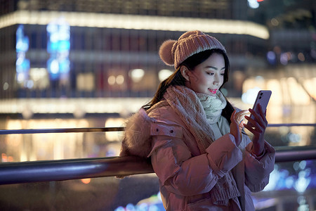 夜间自拍夜晚使用手机自拍的冬季女性背景