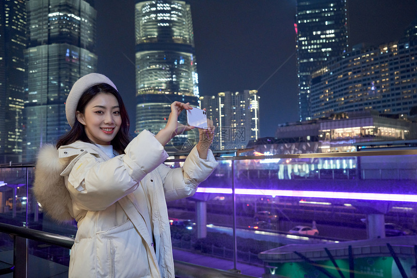 使用手机拍夜景的都市女性图片