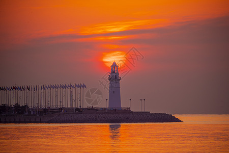 红色太阳日出时红彤彤的海和伫立的灯塔背景