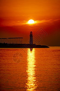 日出时红彤彤的海和伫立的灯塔高清图片