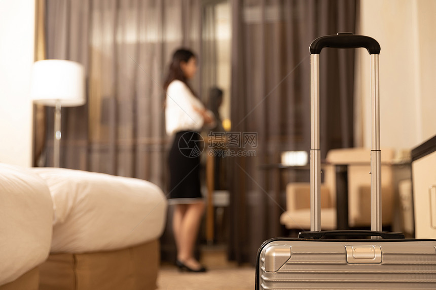 入住酒店的商务女性站在床边图片