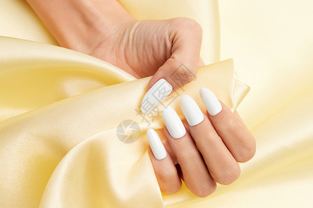女性美甲手部特写握着丝绸背景图片