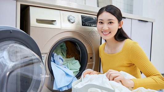 做家务的女性把脏衣服放入洗衣机背景图片