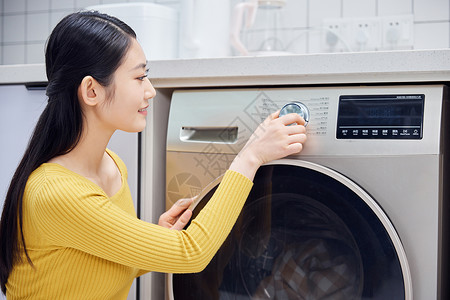家庭主妇控制洗衣机按钮清洗衣物图片