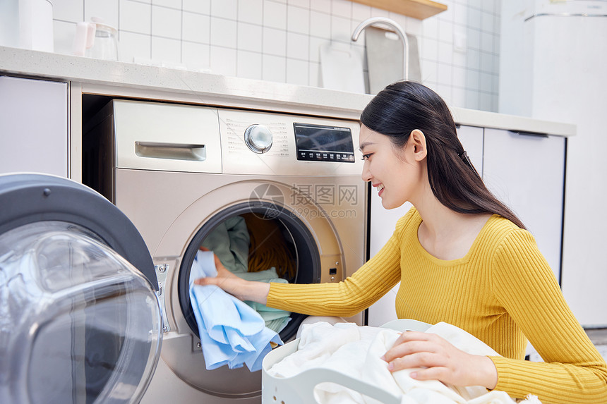 做家务的女性把脏衣服放入洗衣机图片