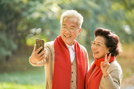 老年人自拍老年夫妇公园里用手机自拍背景