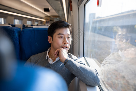 坐在火车上的男性看着窗外风景高清图片