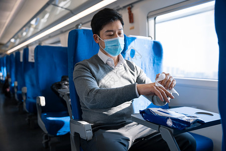男性在列车上使用消毒湿巾擦手图片