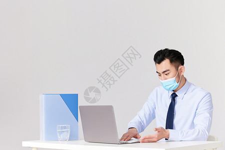 戴着口罩的男性使用消毒湿巾擦拭电脑图片