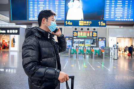 春节回家戴着口罩站在入站口打电话的男性高清图片