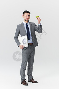 手拿体重秤和青苹果的职场男性图片