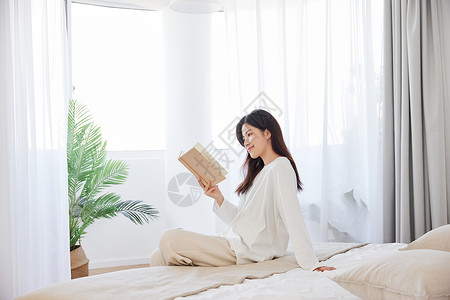 女伸懒腰周末早晨看书的居家女性背景