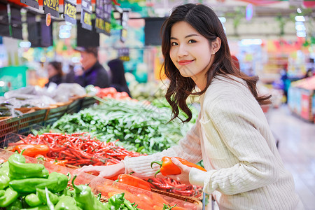 年轻女性超市挑选购买蔬菜背景图片
