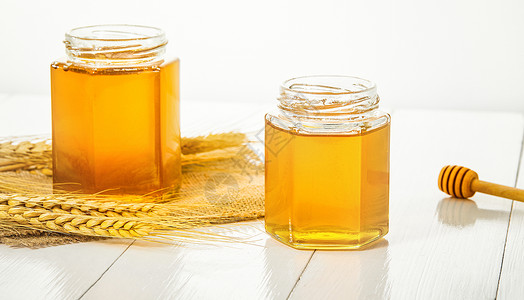 白色桌面上的蜂蜜罐子高清图片