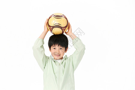 爱健身爱锻炼的小男孩把足球举到头顶背景