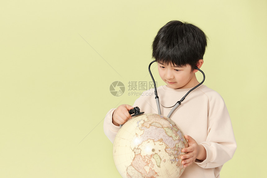 小男孩用听诊器对着地球图片