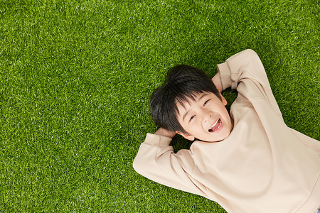 自由自在躺在草地玩耍的小男孩高清图片