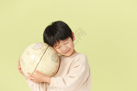闭着眼睛抱着地球的小男孩背景图片