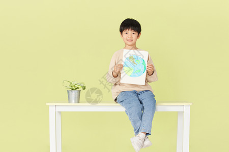 手绘绿植白掌坐在桌子上的小男孩拿着手绘的地球背景