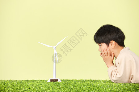 童真世界趴在草地上看着风力发电机模型的小男孩背景