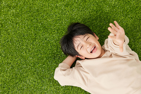 躺草坪上开心的躺在草坪上的小男孩背景