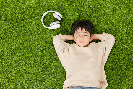 听歌的男孩躺在草坪上闭眼休息的小男孩背景