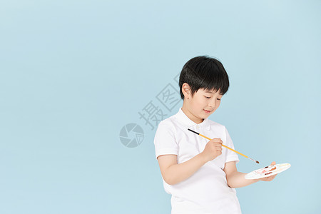低头学习男孩正在画画的小男孩在低头调色背景
