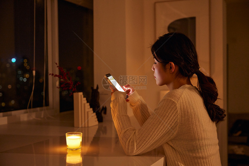 深夜熬夜玩手机的年轻女性图片