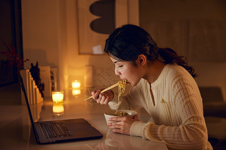 居家女性熬夜看剧吃泡面背景图片