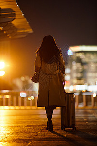 行李箱人夜晚都市女性手提行李箱走在路上背景