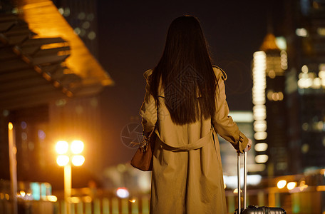 在路上的人夜晚都市女性手提行李箱走在路上背景