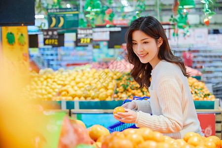 超市购物挑选橘子的青春女性背景图片