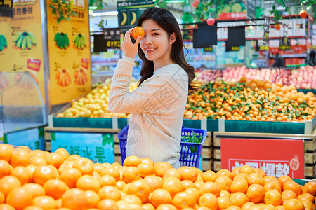 超市购物挑选橘子的青春女性背景图片
