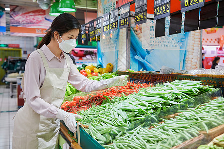 佩戴口罩的超市服务员整理蔬菜区高清图片