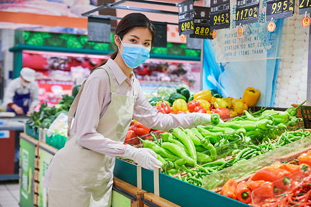佩戴口罩的超市服务员整理蔬菜区高清图片