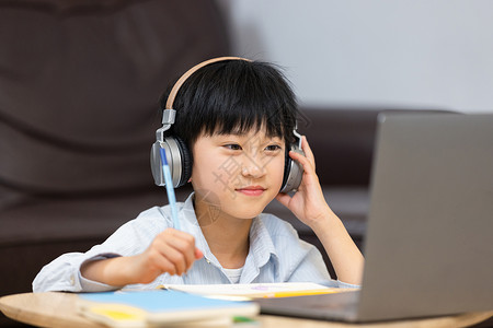 耳机学生在家上网课认真听讲的小男孩背景